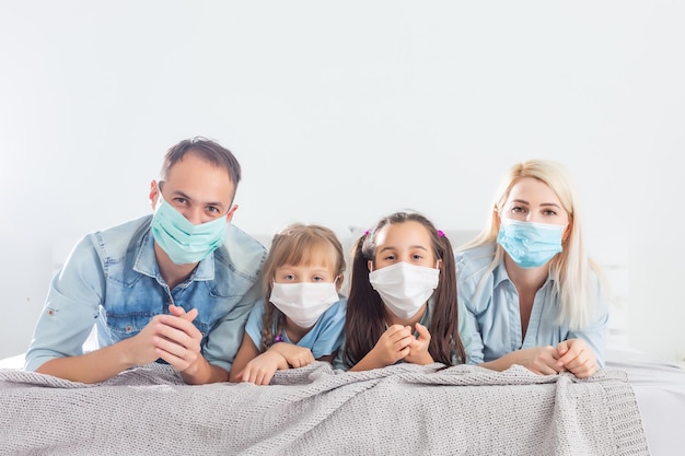 Família em quarentena, isolamento em casa enquanto coronavírus, marido, esposa e filhos na cama, família com máscaras faciais