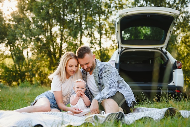 Família em uma floresta. Pessoas perto do carro. Fundo do pôr do sol.