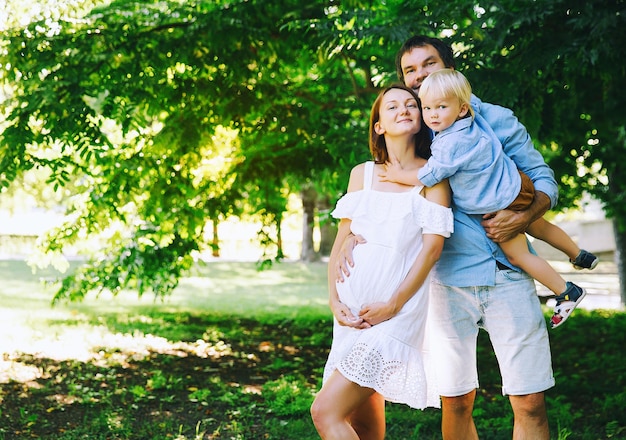 Familia embarazada a la espera de un bebé Esposo y esposa embarazada con un niño pequeño en la naturaleza de verano