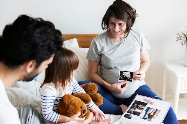 Foto familia embarazada mirando a través de un álbum de fotos familiar