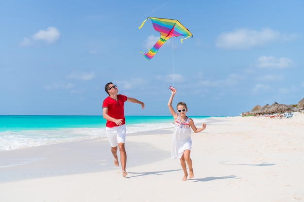 Família empinando pipa juntos na praia tropical branca