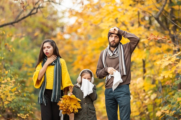 Familia enferma de pie en un bosque otoñal