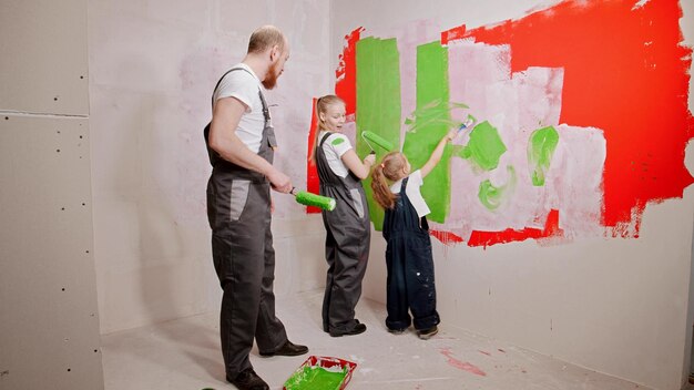 Família engraçada pintando paredes no novo apartamento em cores verdes e vermelhas