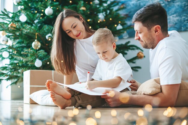 Família escrevendo uma carta para o Papai Noel perto da árvore de Natal