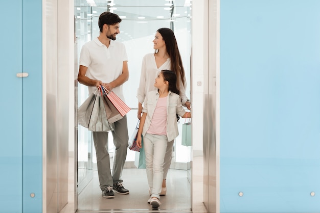 La familia está saliendo del centro comercial con bolsas llenas de compras.