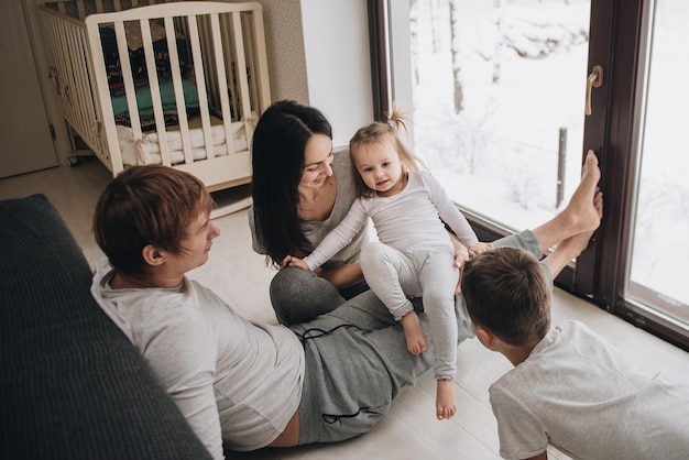 La familia está sentada en la ventana y mirando el bosque de invierno. Buen espíritu de año nuevo. Mañana en pijama.