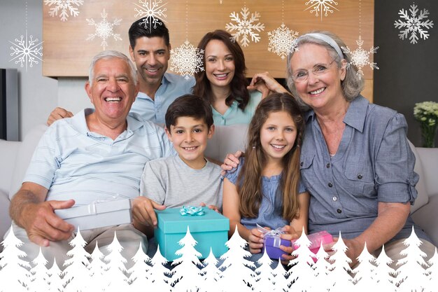 Foto família estendida no sofá com caixas de presente na sala de estar contra floresta de abetos e flocos de neve