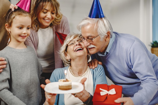 Família estendida surpreendente mulher sênior com presentes e bolo de aniversário em casa