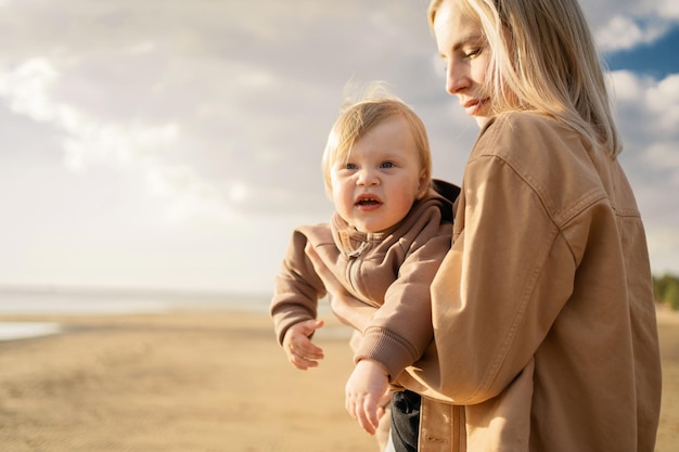 Família estilosa e feliz juntos Mãe e filha estão caminhando juntos perto do oceano