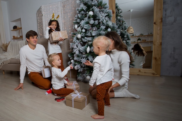 Familia europea sentada cerca del árbol de Navidad