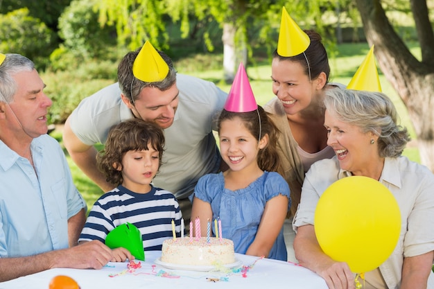 Familia extendida llevando sombreros de fiesta en la celebración de cumpleaños en el parque