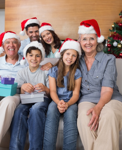 Familia extendida en sombreros de Navidad con cajas de regalo en la sala de estar
