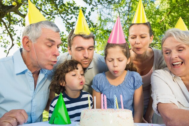 Familia extendida soplando pastel al aire libre