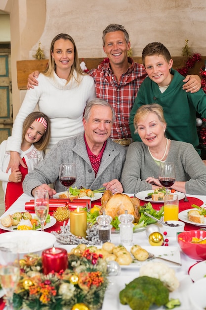 Familia extensa feliz que mira la cámara en el tiempo de la Navidad