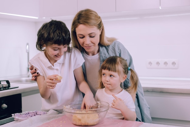 Família faz biscoitos em casa mãe ensina suas filhas a amassar massa na cozinha