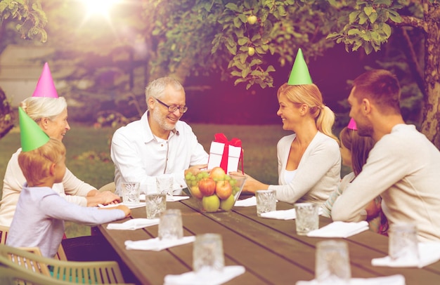 família, felicidade, geração, lar e conceito de pessoas - família feliz com caixa de presente jantando de férias ao ar livre