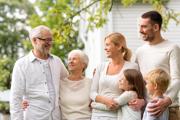 família, felicidade, geração, lar e conceito de pessoas - família feliz em frente à casa ao ar livre