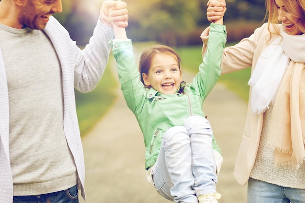 família, felicidade, infância e conceito de pessoas - close-up de feliz mãe, pai e garotinha andando no parque de verão e se divertindo
