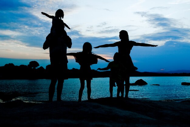 Família feliz à beira-mar na silhueta da natureza