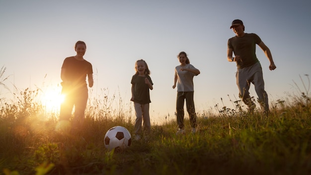 Família feliz a jogar futebol.