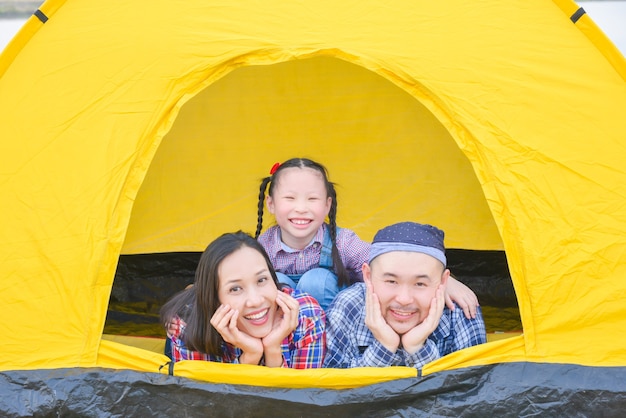 Família feliz acampando nas férias Pai, mãe e filha, deitados juntos na tenda e sorriem