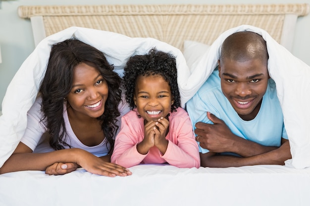 Familia feliz acostada en la cama