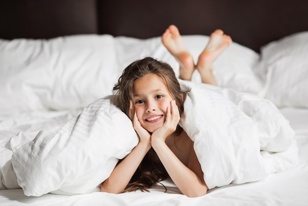 Familia feliz acostada bajo una manta en la cama en casa