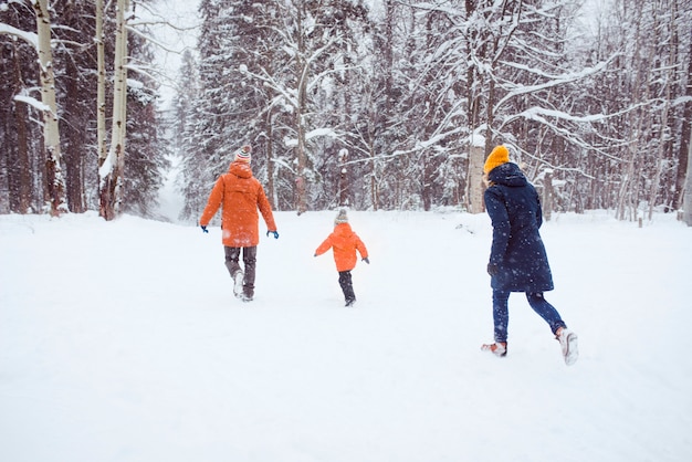 família feliz administrada na floresta de neve do inverno