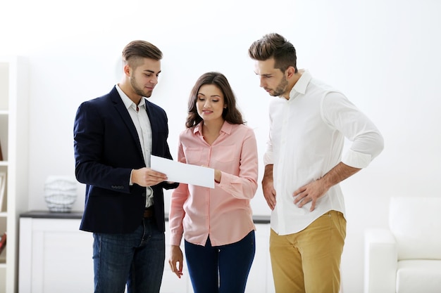 Familia feliz con agente inmobiliario sobre fondo claro