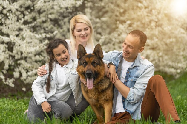 Foto familia feliz al aire libre pasando tiempo juntos. padre, madre e hija se divierten en un césped floral verde.