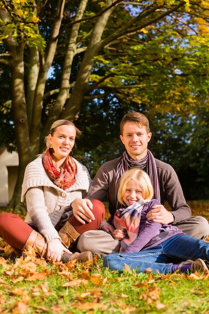 Familia feliz al aire libre sentado en el césped en otoño