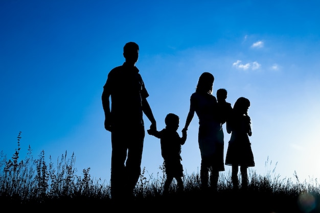 Familia feliz al aire libre en la silueta del parque