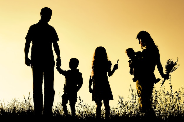 Familia feliz al aire libre en la silueta del parque