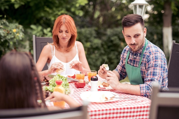 Familia feliz almorzando en el jardín