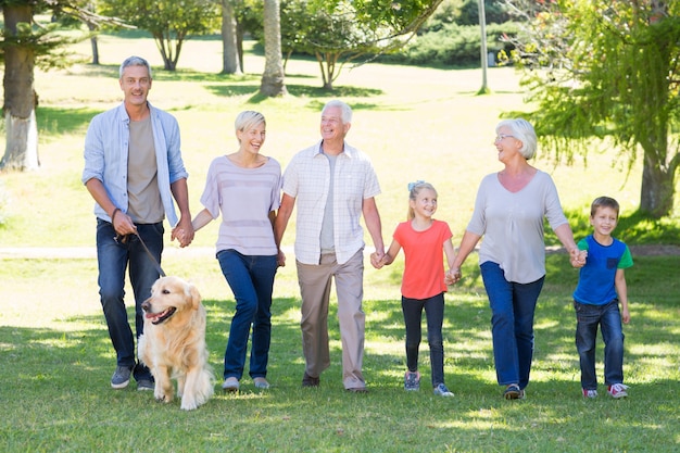 Família feliz andando no parque com seu cachorro