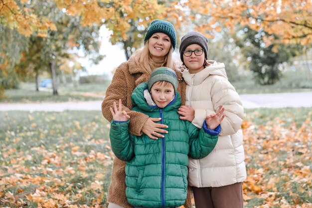 Família feliz andando no parque ensolarado e joga laranja maple deixa mãe com crianças aproveitando o clima de outono ao ar livre