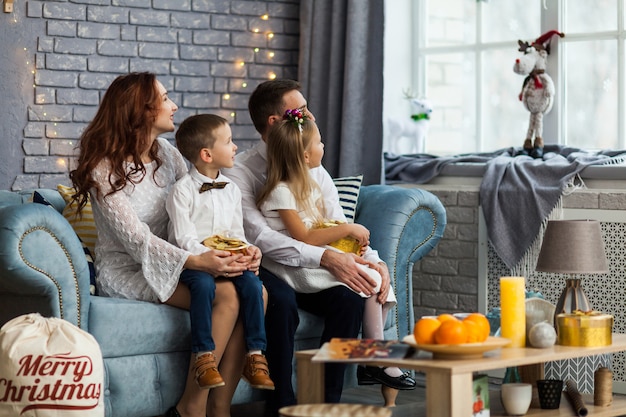 Familia feliz antes de Navidad mirando la ventana