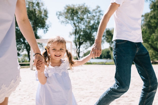 Família feliz ao ar livre a passar tempo juntos. Pai, mãe e filha estão se divertindo e correndo na praia