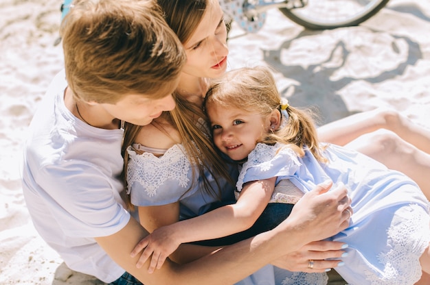 Família feliz ao ar livre a passar tempo juntos. Pai, mãe e filha se divertem e brincando na praia