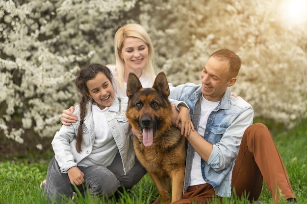 Família feliz ao ar livre, passando tempo juntos. Pai, mãe e filha estão se divertindo em uma grama verde floral.