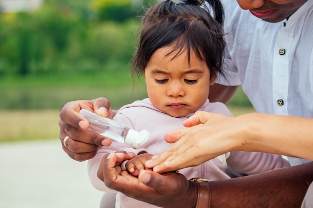 Familia feliz aplicando gel antibacteriano desinfectante de manos a las manos de la hija