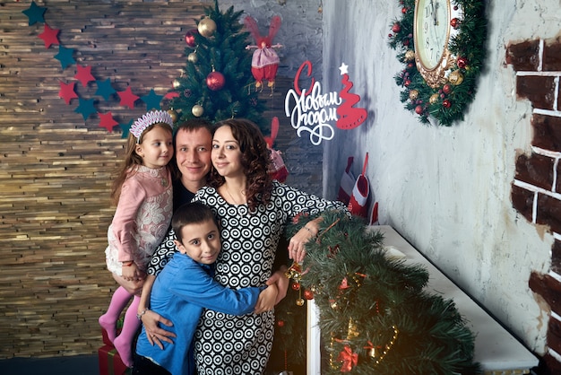 Foto familia feliz en el árbol junto a la chimenea. mamá, papá y dos niños en vacaciones de invierno. nochebuena y nochevieja.