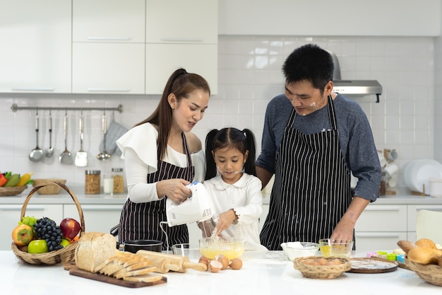 Familia feliz de asia con hija haciendo masa preparando galletas para hornear, hija ayuda a los padres a preparar el concepto de familia hornear