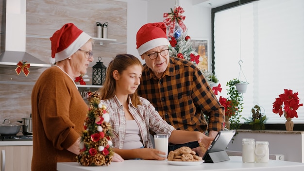 Família feliz assistindo a vídeos de natal da infância on-line usando um tablet