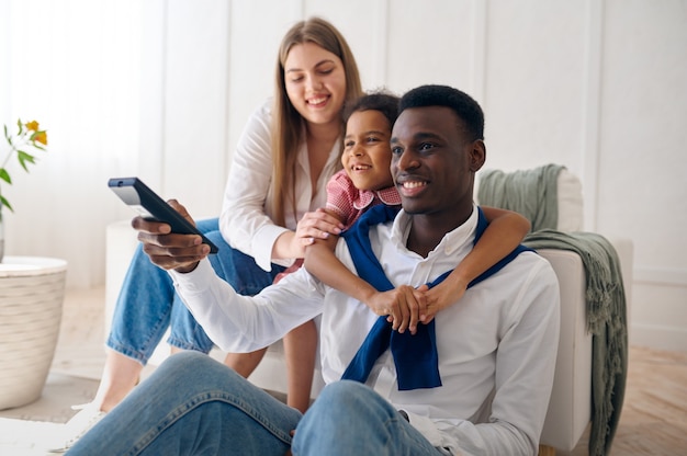 Família feliz assistindo tv na sala