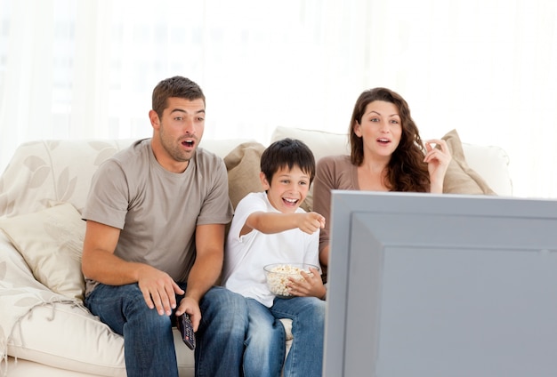 Família feliz assistindo um filme na televisão juntos no sofá