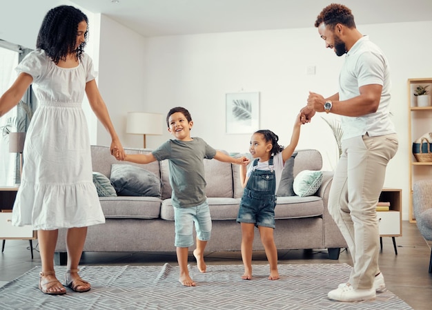 Familia feliz bailando y divirtiéndose mientras comparte energía de amor y vínculo mientras se toma de la mano en la sala de estar en casa Hombre mujer y hermanos niños jugando y riendo disfrutando juntos del tiempo activo