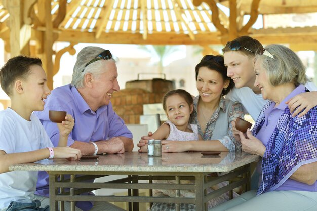 Família feliz bebendo chá à mesa ao ar livre no verão