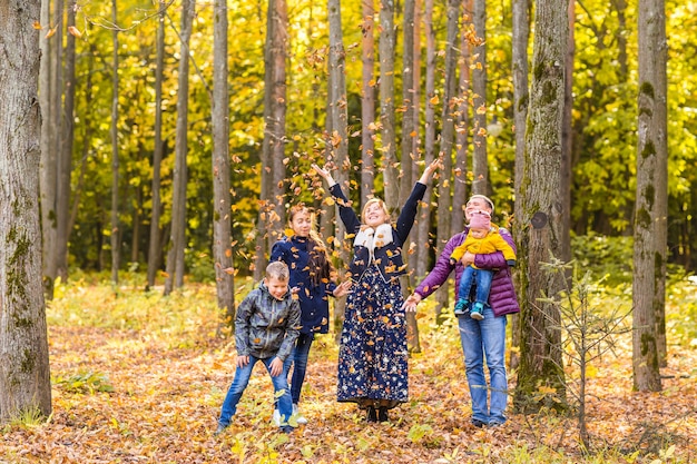 Família feliz brincando com folhas de outono no parque