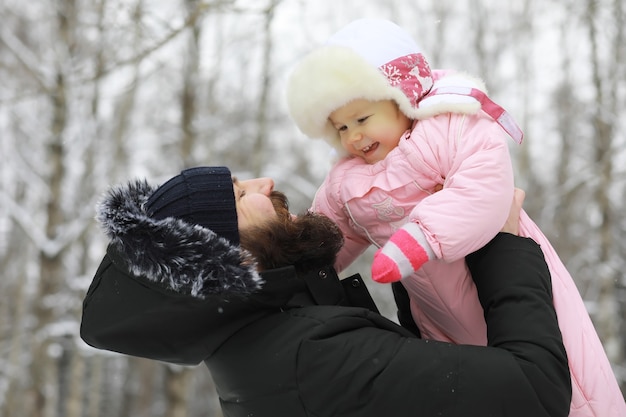 Família feliz brincando e rindo no inverno ao ar livre na neve. Dia de inverno do Parque da cidade.